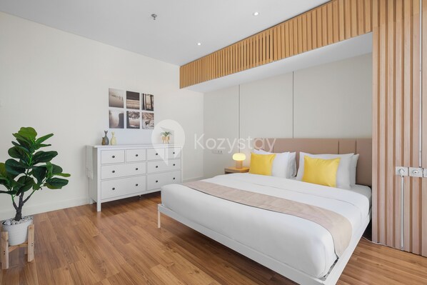 Une chambre moderne avec un grand lit, une commode blanche et un mur recouvert de panneaux en bois.