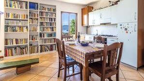 A cozy kitchen with a dining table set for two, surrounded by bookshelves filled with books.