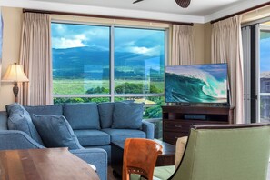A living room with a large window, a sofa, a TV, and a table.