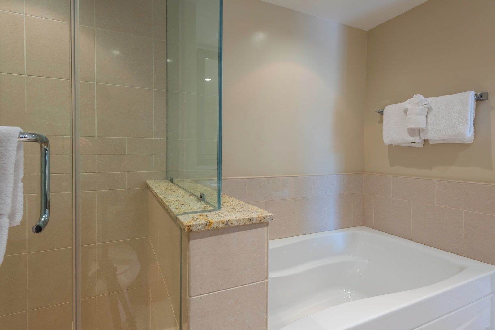 Une salle de bain avec une douche à parois de verre, une baignoire et un porte-serviettes avec des serviettes.