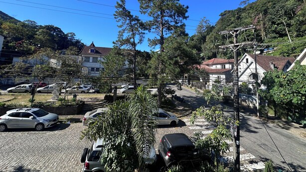 A residential area with parked cars, houses, and trees.