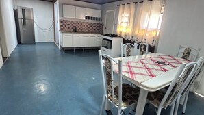 A compact kitchen with a refrigerator, stove, and white cabinets.