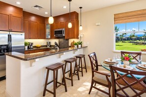 Una cocina moderna con armarios de madera, electrodomésticos de acero inoxidable y una isla grande con taburetes de bar.