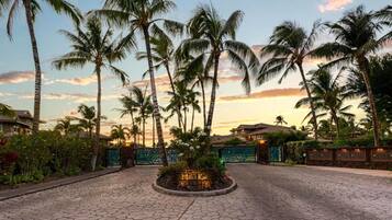 A paved entrance area with a circular garden, palm trees, and a gate labeled "Hali'i Kai".
