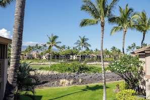 Un resort con varias edificaciones, palmeras y un jardín ajardinado con césped y arbustos.