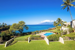 Ein Pool mit Blick auf den Ozean und ein Berg in der Ferne.