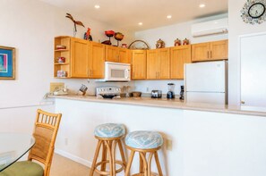 A kitchen with wooden cabinets, a microwave, a refrigerator, a toaster, and a blender on the counter. - Napili Point | Oceanfront 5 BR, Sleeps 14 | Car Incl. w/ 6+ Nights | NAP ML-1301 by KBM (Lahaina)
