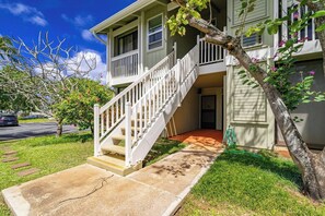 A two-story house with a front porch, a staircase, and a tree in the yard.