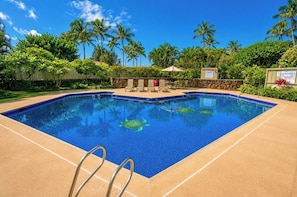 Une piscine rectangulaire à l’eau d’un bleu limpide, entourée d’une terrasse de couleur beige.