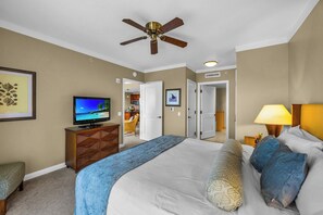 A hotel room with a bed, a television, a ceiling fan, and a door leading to a bathroom. - Honua Kai | Ocean View 4 BR, Sleeps 14 | Car Incl. w/ 6+ Nights | HKK ML-1305 by KBM (Lahaina)