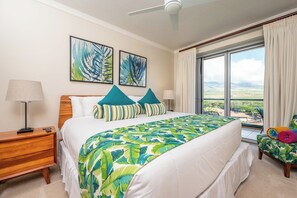 A hotel room with a bed, a nightstand, a lamp, a window with curtains, and two wall-mounted paintings.