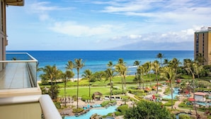 A resort with a pool, palm trees, and a view of the ocean.