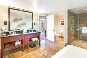 Un baño moderno con un espejo grande, lavamanos dobles, tocador, zona de ducha y retrete.