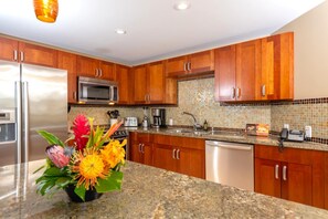 Una cocina moderna con armarios de madera, electrodomésticos de acero inoxidable y encimera de granito.