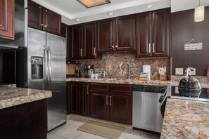 A modern kitchen with dark wood cabinets, stainless steel appliances, and a granite countertop.