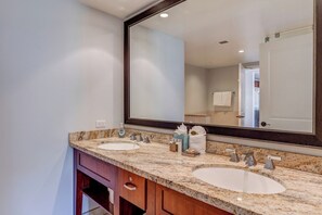 Une salle de bain avec deux lavabos, un grand miroir et un meuble-lavabo avec un placard.