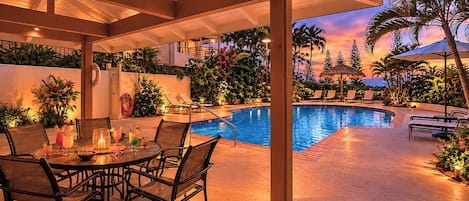 Un espace piscine extérieur abrité, avec des chaises longues, une table où l’on peut prendre un verre et des plantes tropicales.