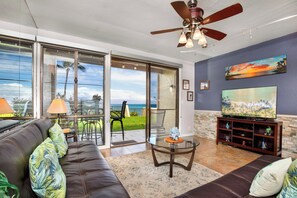 A living room with a sofa, TV, and a balcony with a view.