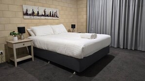 A modern bedroom with a bed, nightstands, a lamp, and a painting on the wall. - Esperance Break Away (Esperance)