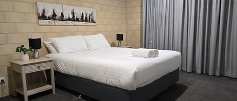 Un dormitorio moderno con una cama, mesitas de noche, una lámpara y un cuadro en la pared.