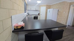 A kitchen with a black countertop, white cabinets, and a white door. - Esperance Break Away (Esperance)