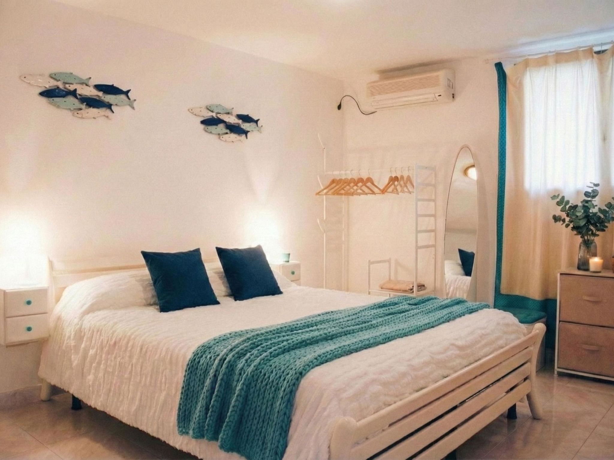 A bedroom with a bed, two bedside tables, a wardrobe, a mirror, and wall decorations.