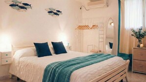 A bedroom with a bed, two bedside tables, a wardrobe, a mirror, and wall decorations.