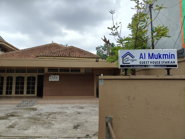 A guest house named Al Mukmin with a tiled roof and a signboard.