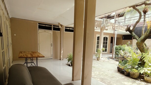 A spacious indoor area with a sofa, pillars, and potted plants. - Griya Al Mukmin (Surakarta)