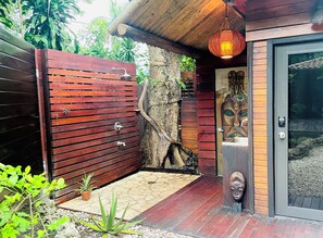 Une porte en bois dont le tronc d’un arbre est intégré au design, une petite plante en pot et une porte dotée d’un panneau de verre et d’une sculpture en bois.
