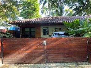 A house with a tiled roof, a wooden gate, and a parked car. - Miami Tiny House • Urban Glamping Solo Micro Space in Posh Coconut Grove (Miami)