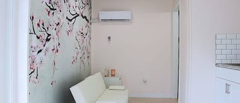 A modern kitchen with white cabinets, a white countertop, and a wall-mounted air conditioner.