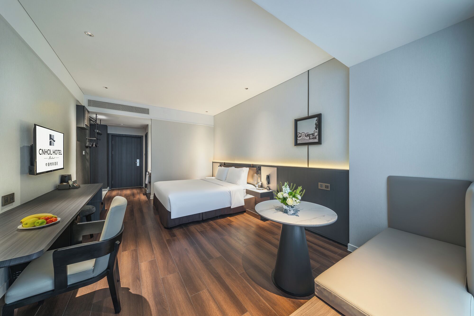 A hotel room with a bed, a desk, a chair, a small table, and a couch.