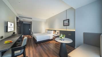 A hotel room with a bed, a desk, a chair, a small table, and a couch.