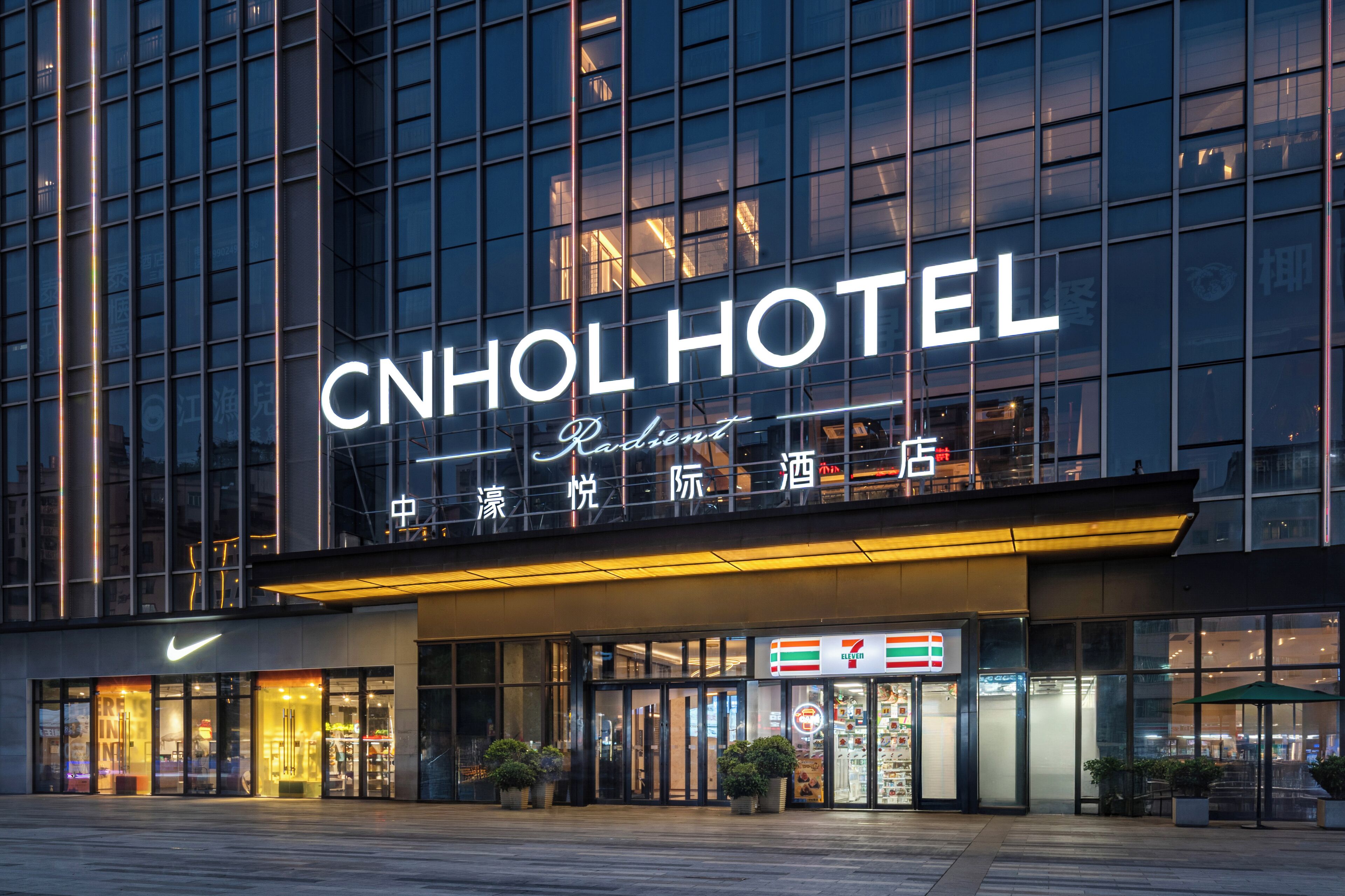 The CNHOL HOTEL with a prominent sign, large windows, and a 7-Eleven store across the entrance.