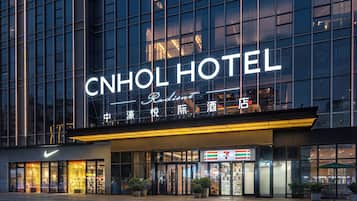 The CNHOL HOTEL with a prominent sign, large windows, and a 7-Eleven store across the entrance.