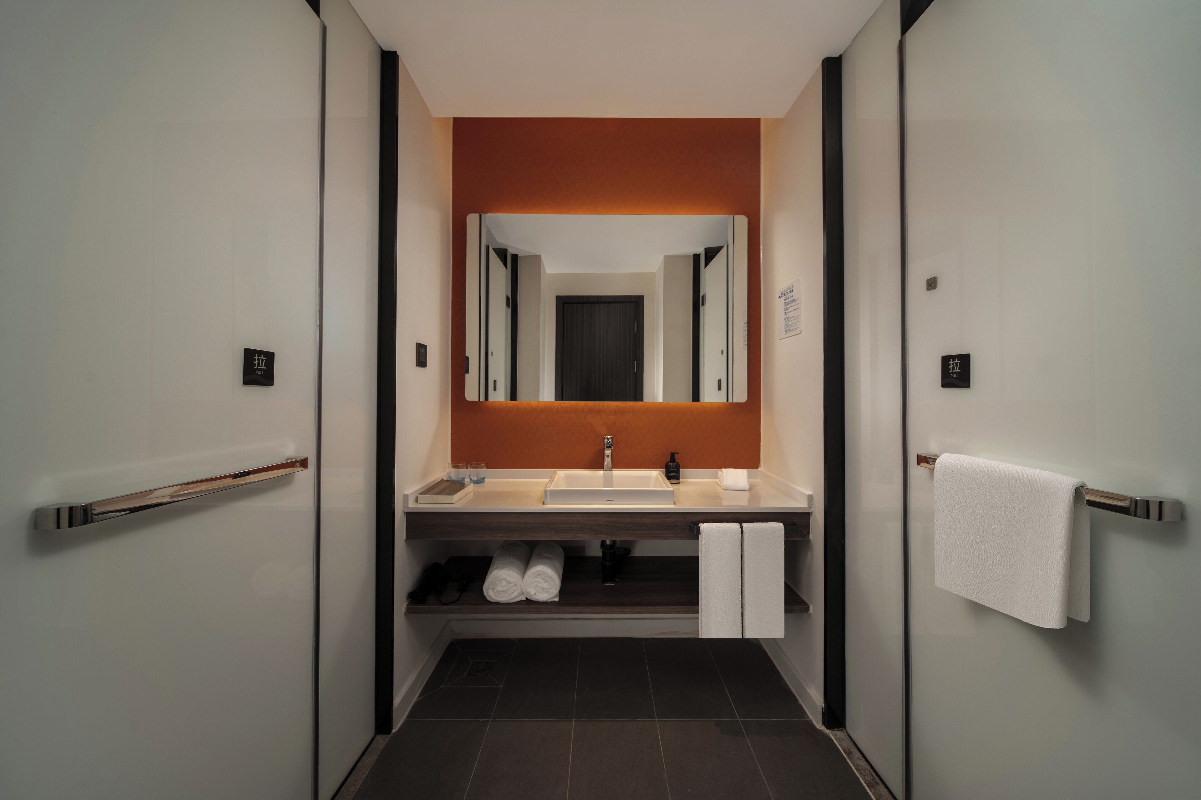 A modern bathroom with a white sink, mirror, and towel rack.