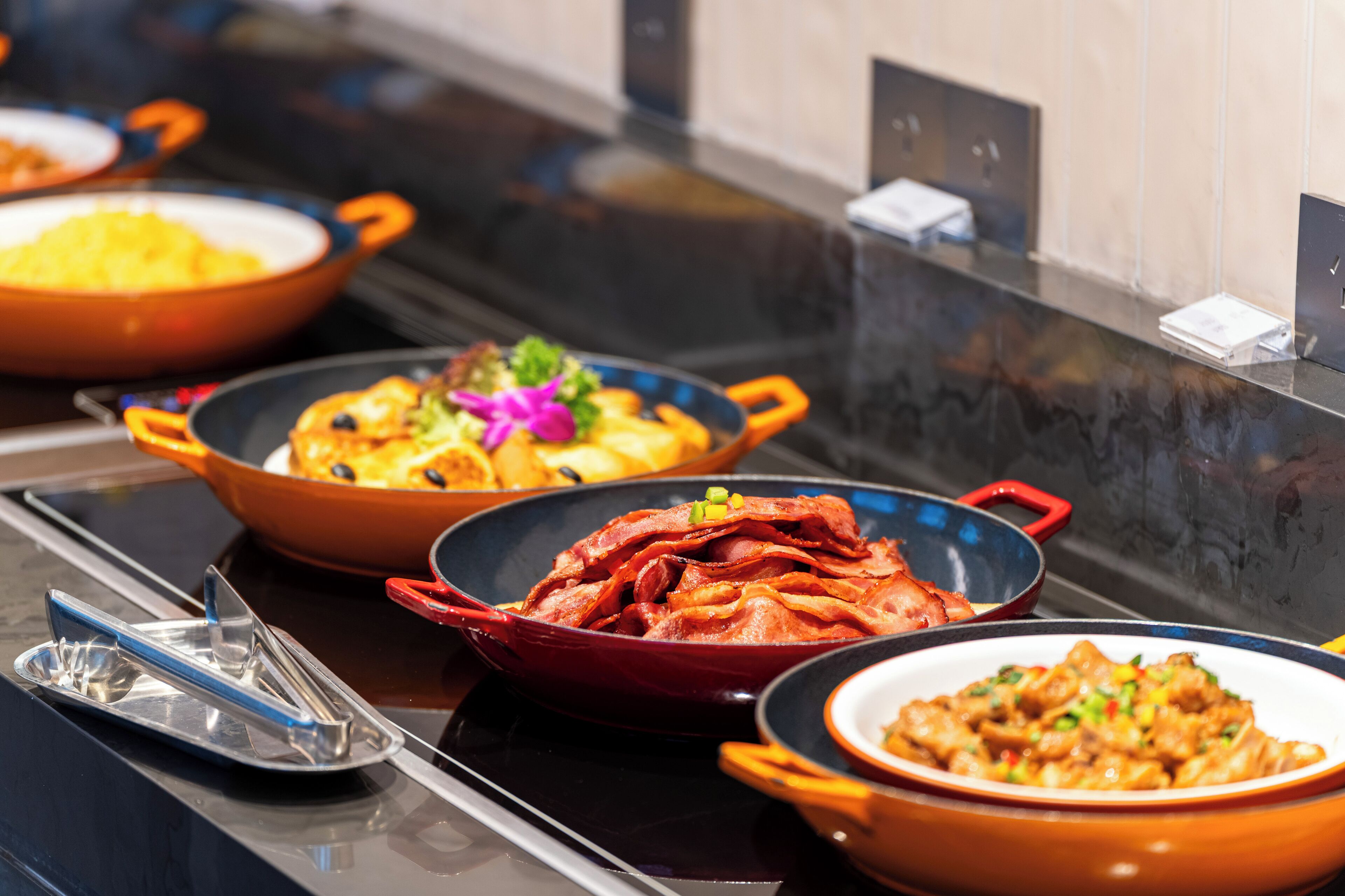 A buffet table with various dishes in colorful serving dishes.