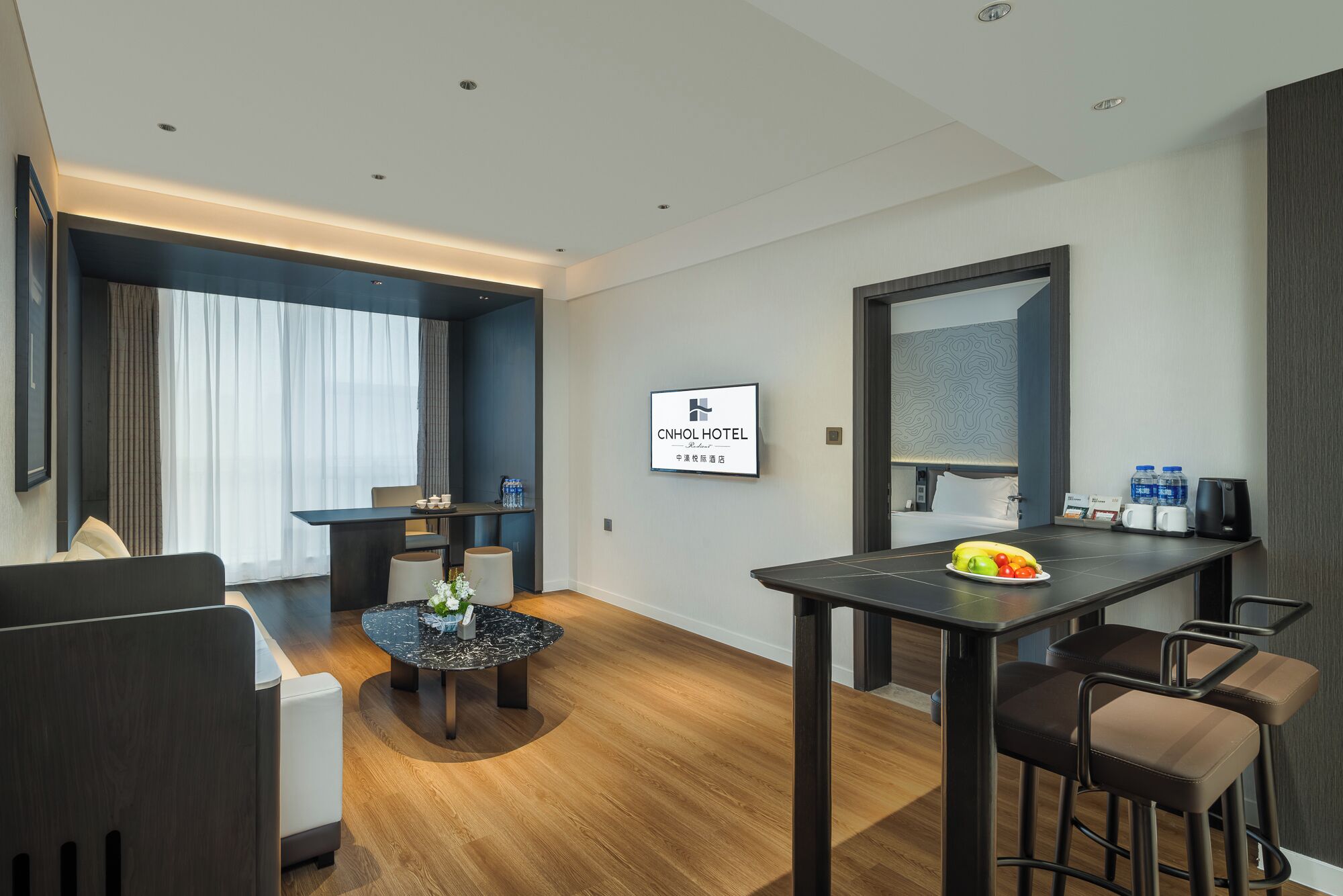 A modern hotel room with a dining area, a bed, and a large mirror.