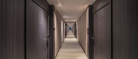 A long, narrow hallway with dark wooden doors on both sides and a carpeted floor.
