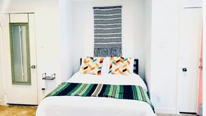 A bedroom with a bed, a wall hanging, and a door. - ‘Señorita Sunset’ Guest Fave! Chic Studio Montrose Walkable area! (Houston)
