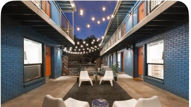 An indoor courtyard with brick walls, white plastic chairs, and string lights. - ‘Señorita Sunset’ Guest Fave! Chic Studio Montrose Walkable area! (Houston)