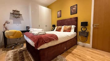 A bedroom with a bed, a desk, a chair, and a door.