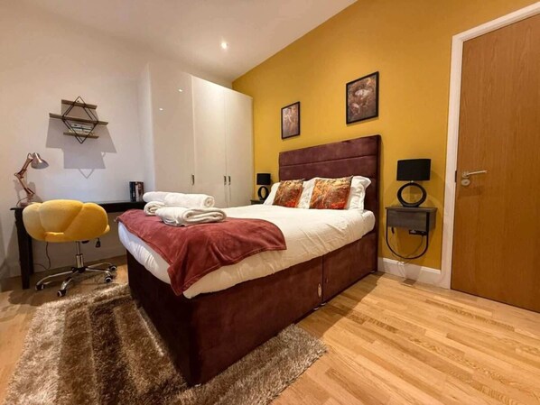 A bedroom with a bed, a desk, a chair, and a door.