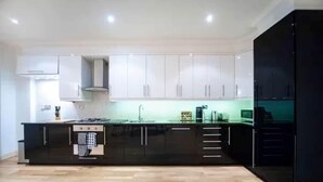 A modern kitchen with white cabinets, a black countertop, and a wooden floor.