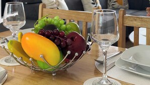 A dining area with a fruit bowl, wine glasses, and a table set for two. - Bright Angel 2 BR Duplex with Balcony Sleeps 5 (London)
