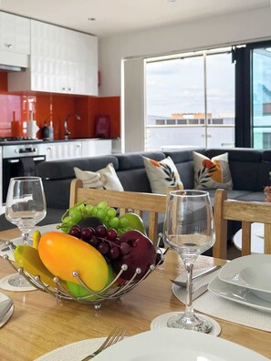 A dining area with a fruit bowl, wine glasses, and a table set for two. - Bright Angel 2 BR Duplex with Balcony Sleeps 5 (London)