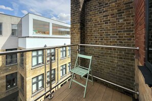A balcony with a metal railing, a green chair, and a view of adjacent buildings. - Bright Angel 2 BR Duplex with Balcony Sleeps 5 (London)