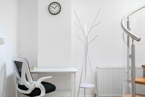 A modern, minimalistic room with a white desk, a chair, a coat rack, and a clock on the wall. - Bright Angel 2 BR Duplex with Balcony Sleeps 5 (London)