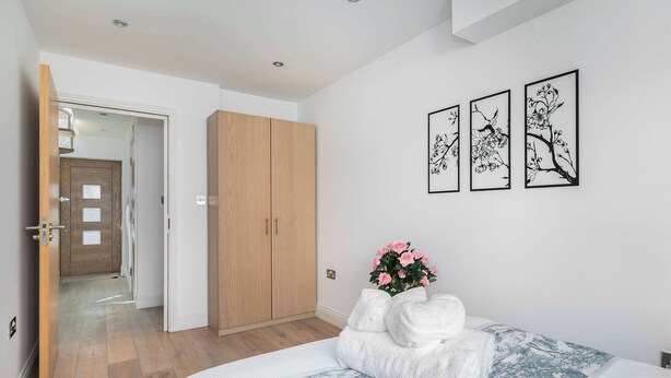 A bedroom with a bed, a wardrobe, and three framed wall art pieces. - Bright Angel 2 BR Duplex with Balcony Sleeps 5 (London)